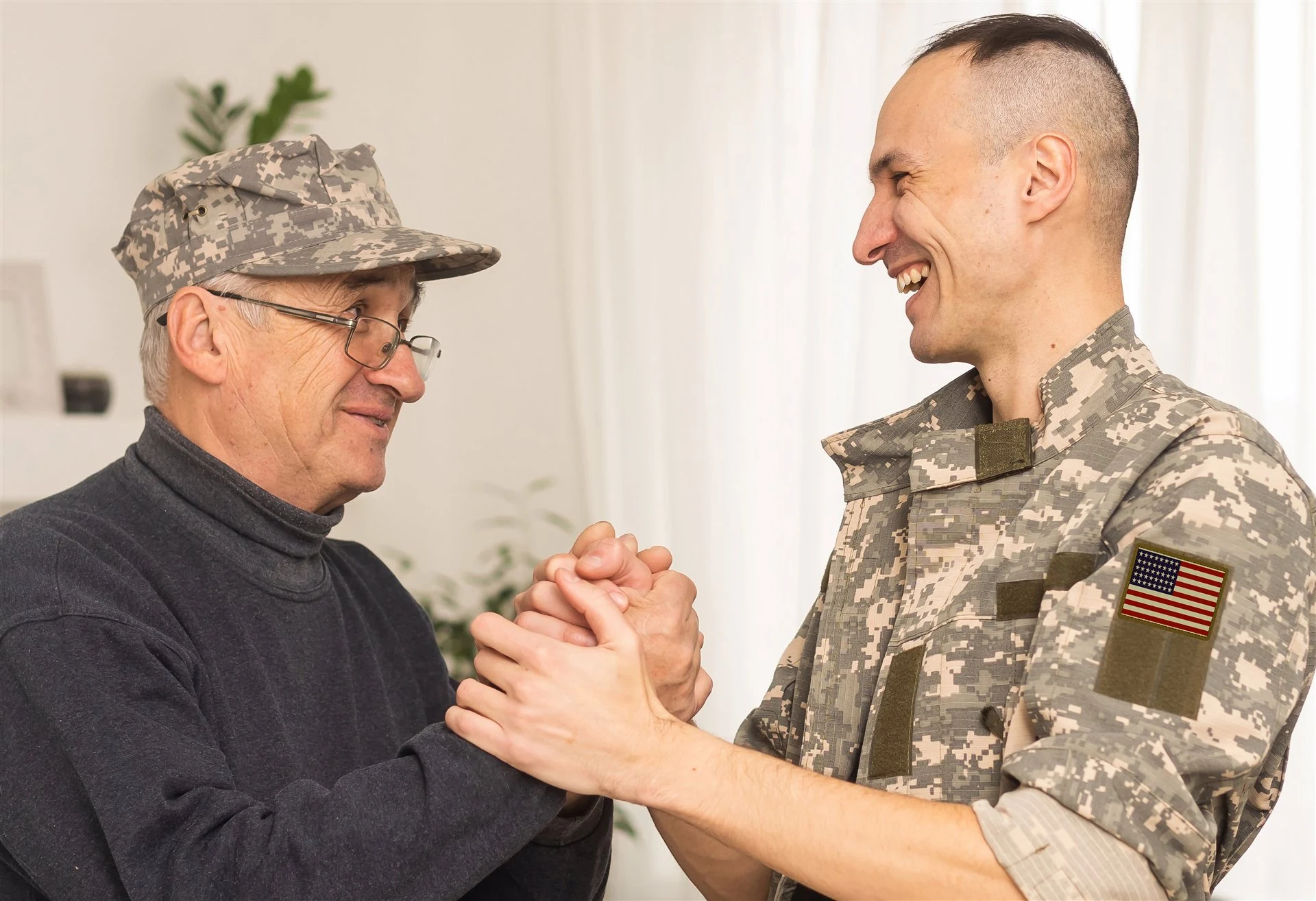 A veteran and a service member sharing a warm smile and a handclasp